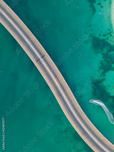 An Aerial photo of an cars passing on a bridge over beautiful turquoise water