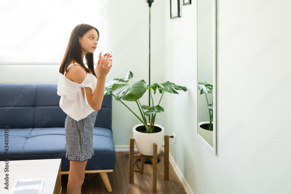 Caucasian kid doing her hair in the mirror