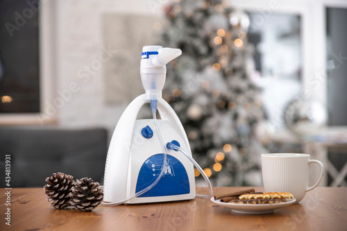Nebulizer on the table with a cup and fir cones in the room photo