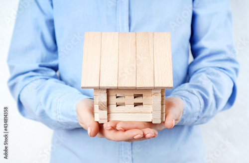 Wooden house model in female hands. Buying, renting or mortgaging a home concept.