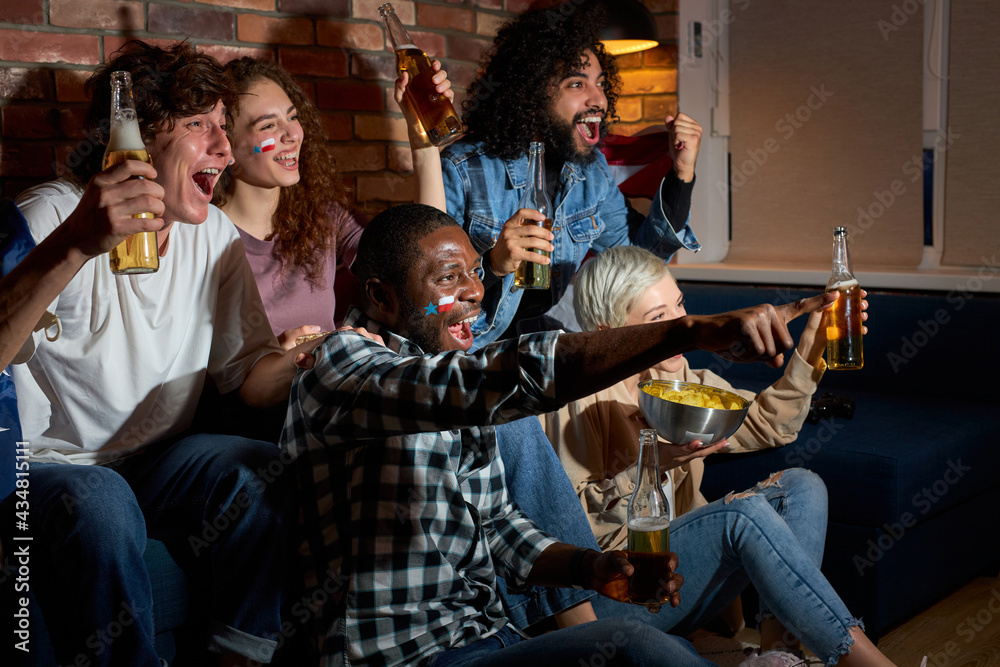 Obraz premium Happy yelling students friends fans having day-off resting eating popcorn and drinking beer, celebrating goal or win of their favourite team