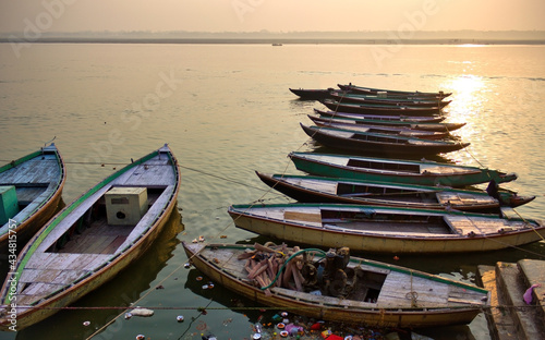 Wallpaper Mural Varanasi, India: Bunch of old wooden colorful boats docked in the bay of Ganges river bank during sunset sunrise against foggy weather. The holy place for hindu religion. Torontodigital.ca