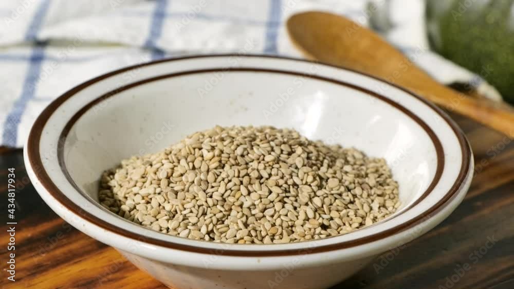 Pouring toasted sesame seeds into a small bowl Pouring toasted sesame seeds into a small bowl