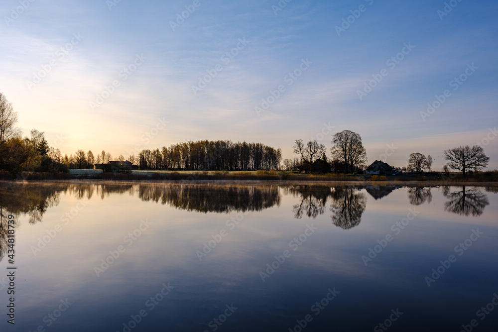 Obraz premium trees by the water with sky reflections