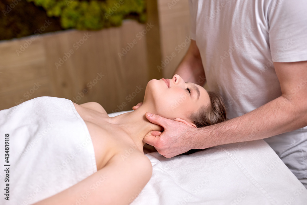Face and Head Massage in beauty spa salon by male therapist. Female enjoying relaxing body and facial massage in spa center. Body care, skin care, wellness, beauty treatment.