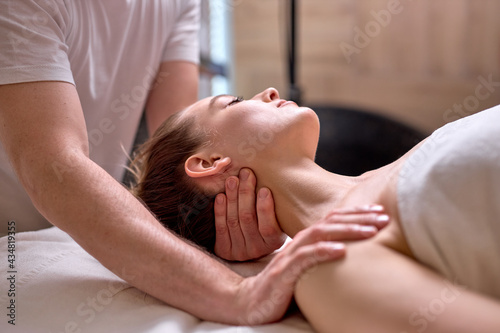 Young female at spa resort, receiving massage on neck and shoulders muscles, enjoying time in spa center, professional masseur at work