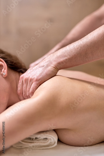 Problems of women body.Healthy massage for young woman in wellness center. Perfect skin. Unrecognizable Skilled Professional Masseur massaging back, shoulders, spine. Close-up photo
