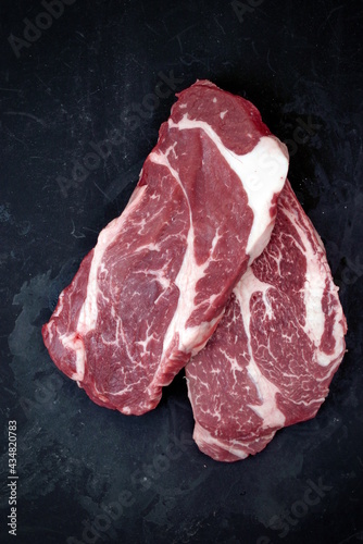 Raw Steak. Sirloin Raw Beef Steak, Overhead View. Single Raw Striploin Steak from Marbled Beef on Black Background. Black Angus Beefsteak Meat. Raw Sirloin Cut. Uncooked Prime Beef Steak.