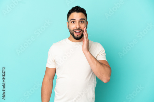 Young arab man isolated on blue background with surprise and shocked facial expression