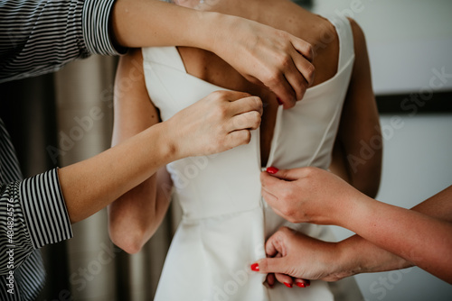 bride zipping buttoning her white wedding dress preparations 