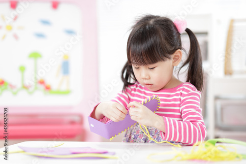 young girl sweing pad craft using plastic needle and yarn for homeschooling