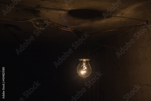 The old incandescent lamp with a tungsten filament. Light bulb close-up isolated black background.