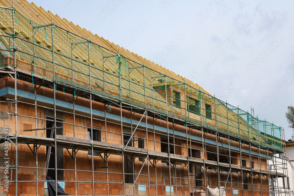 Scaffolding around a brick building under construction. Orange bricks.