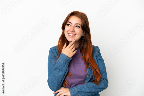 Young redhead woman isolated on white background looking up while smiling