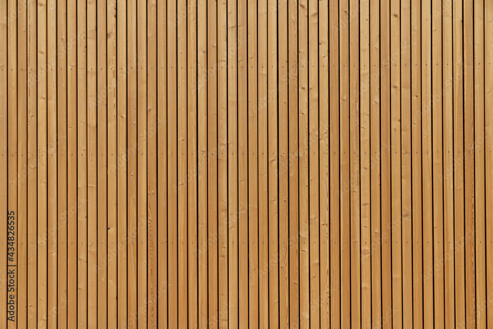 Fototapeta premium Facade sheathing made of wooden vertical planks. Warm yellow color.