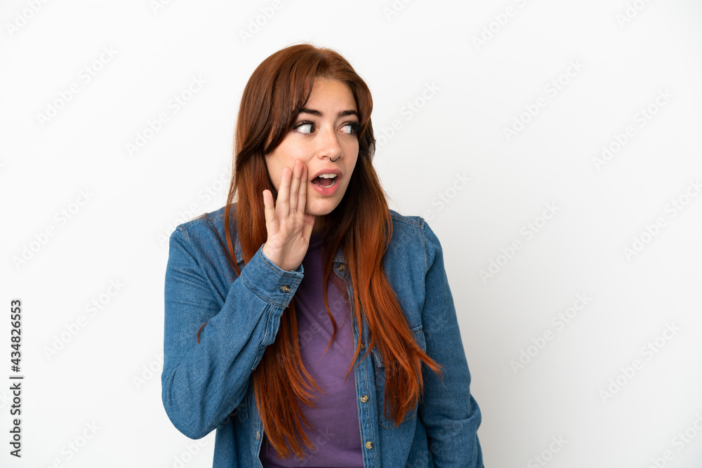 Young redhead woman isolated on white background whispering something with surprise gesture while looking to the side Young redhead woman isolated on white background whispering something with surprise gesture while looking to the side