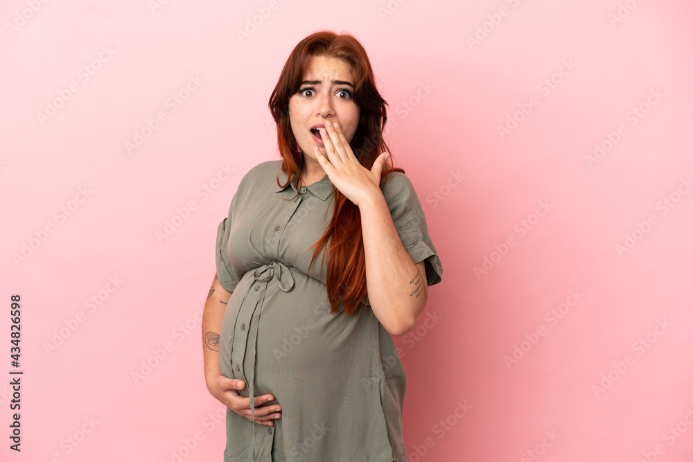 Young redhead caucasian woman isolated on pink background pregnant and doing surprise gesture Young redhead caucasian woman isolated on pink background pregnant and doing surprise gesture