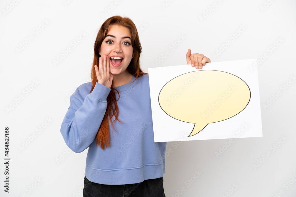 Young redhead woman isolated on white background holding a placard with speech bubble icon and shouting Young redhead woman isolated on white background holding a placard with speech bubble icon and shouting