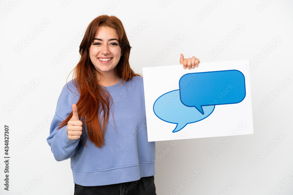 Young redhead woman isolated on white background holding a placard with speech bubble icon with thumb up Young redhead woman isolated on white background holding a placard with speech bubble icon with thumb up