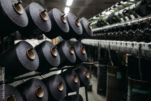 Spools of black cotton thread on a stand near the production line