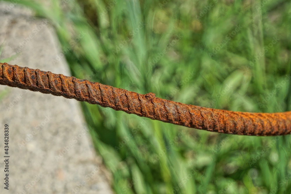 long iron piece of rebar in red rust on gray green background outdoors long iron piece of rebar in red rust on gray green background outdoors