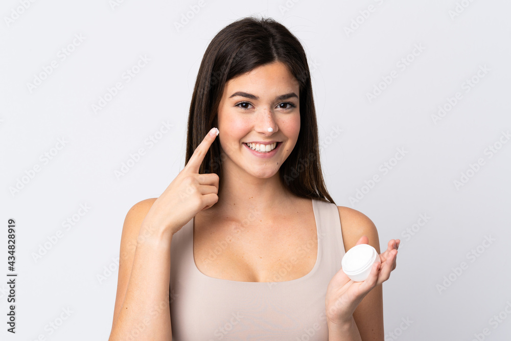 Teenager Brazilian girl with moisturizer over isolated white background Teenager Brazilian girl with moisturizer over isolated white background