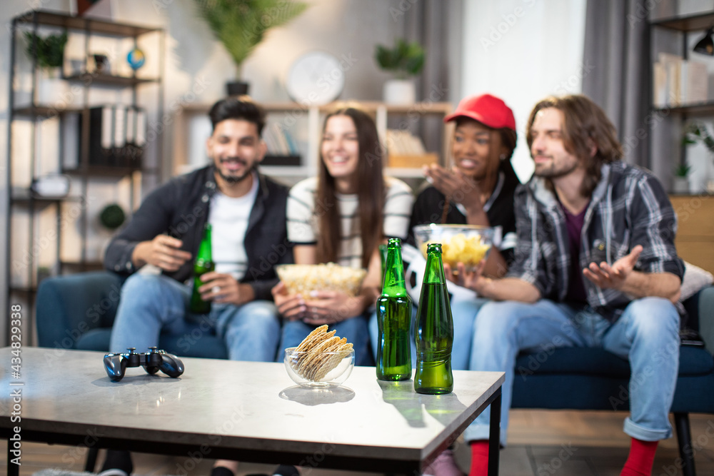 Multiracial men and women in casual outfit eating snacks and drinking beer while supporting favorite football team during world cup. Concept of friendship, sport and entertainment.
