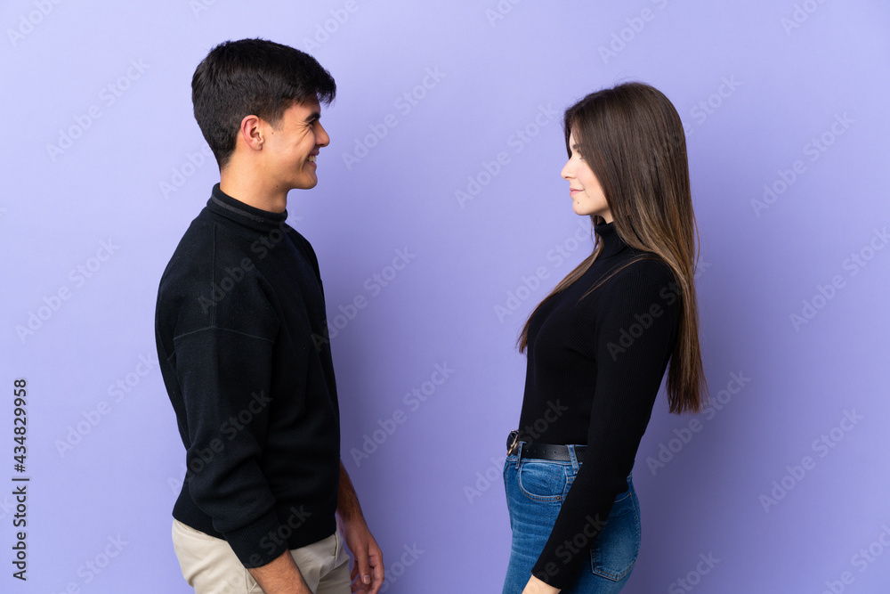 Young couple over isolated purple background looking at each other Young couple over isolated purple background looking at each other