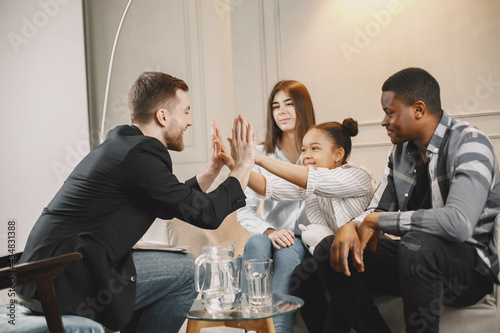 Pshecoterapist clapping hands with little girl at family consultation photo