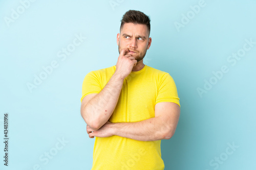 Russian handsome man isolated on blue background nervous and scared