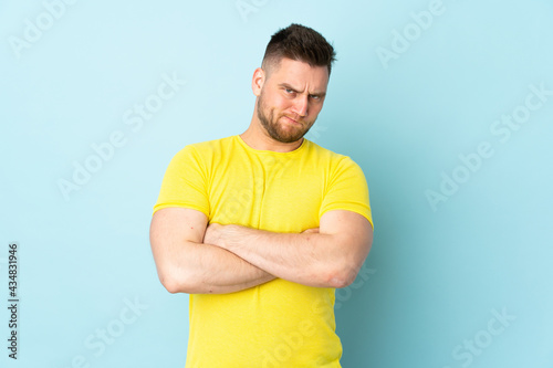 Russian handsome man isolated on blue background with unhappy expression