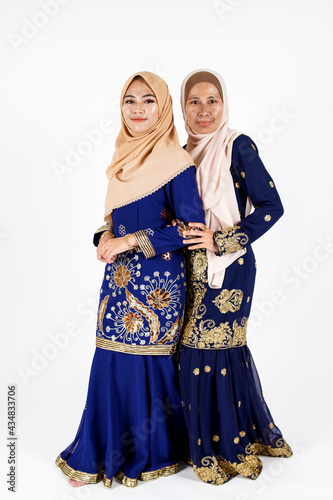 Studio portrait of mother and daughter dressed for an event. Fashion for dinner, event and feast day. Studio shot with white background.