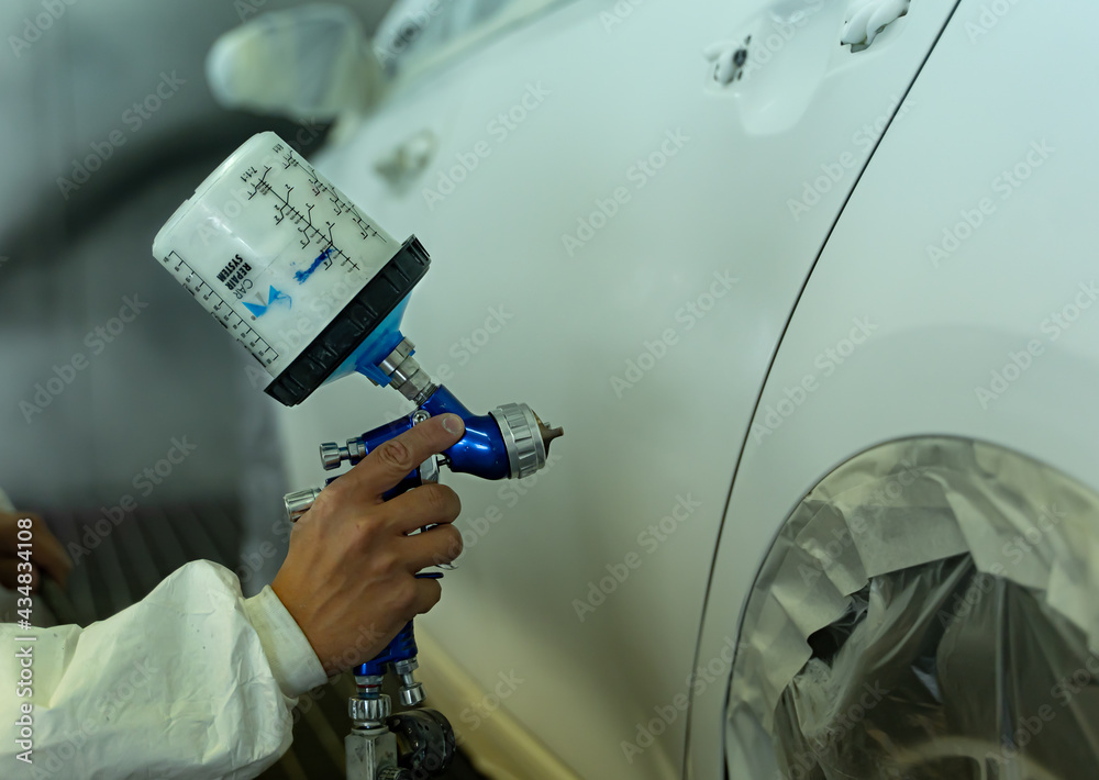 Young man paints car in his garage's box, Madrid
