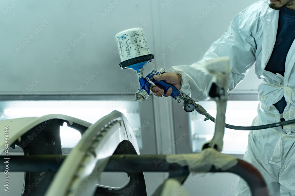 Spanish apprentice boy paints front bumper with great care, Madrid,