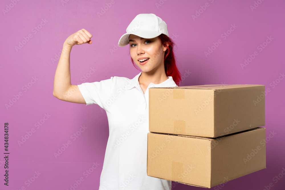 Teenager delivery girl isolated on purple background doing strong gesture Teenager delivery girl isolated on purple background doing strong gesture