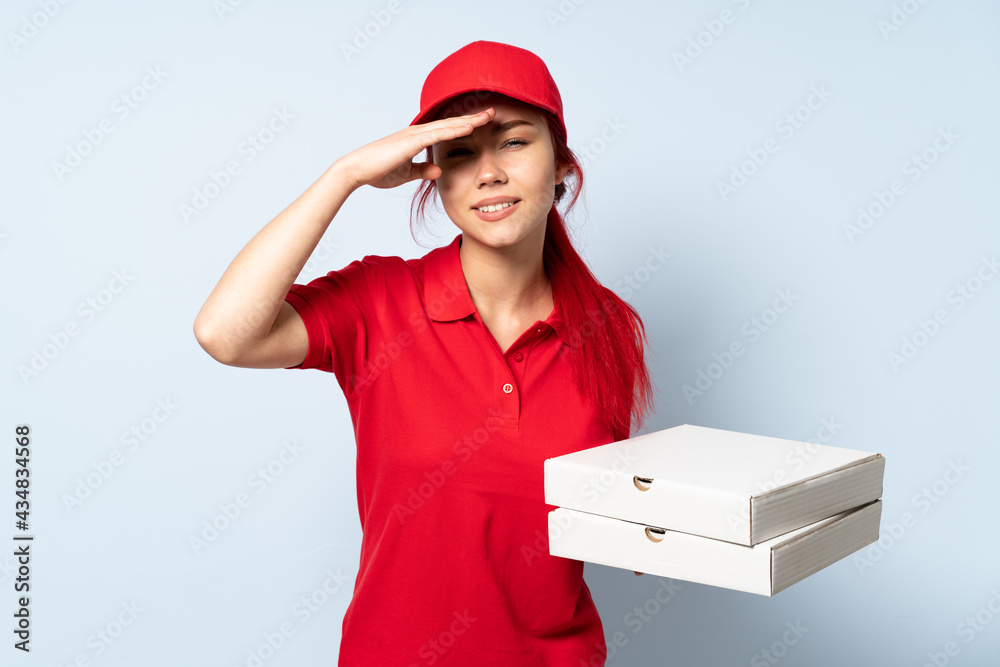 Pizza delivery girl holding a pizza over isolated background looking far away with hand to look something Pizza delivery girl holding a pizza over isolated background looking far away with hand to look something