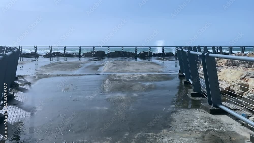 Wet embankment against the background of a not very stormy sea, the waves of which break on the breakwater. HD Wet embankment against the background of a not very stormy sea, the waves of which break on the breakwater. HD