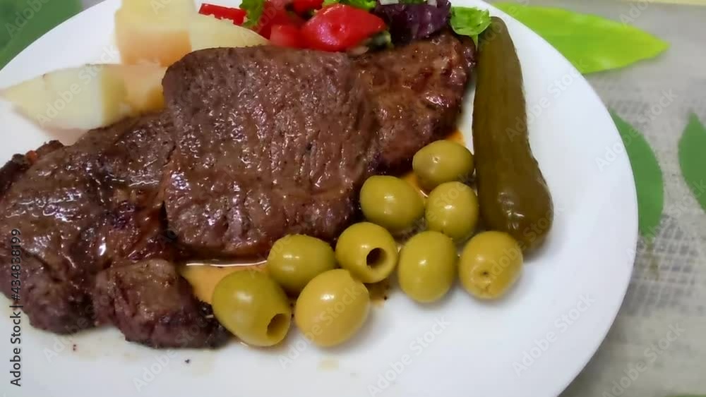 Hot fresh grilled boneless rib eye steak on white with baked potatoes and vegetables. HD Hot fresh grilled boneless rib eye steak on white with baked potatoes and vegetables. HD