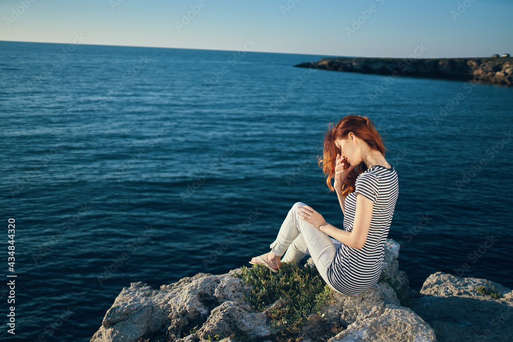 romantic woman on a rock near the sea in the mountains sunset summer back view