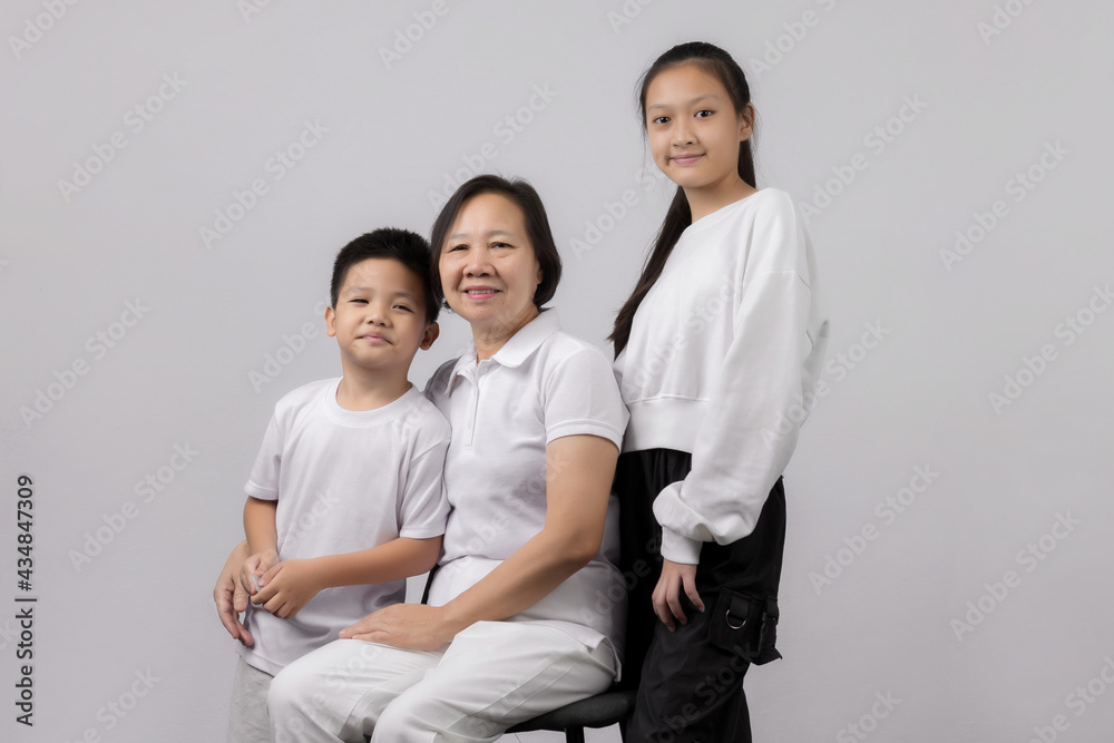 Portrait of Grandmother and grandchild hugging, looking at camera and smiling, on gray background Portrait of Grandmother and grandchild hugging, looking at camera and smiling, on gray background