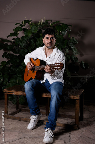 Músico guitarrista en un banco tocando su instrumento.  © Guillermo