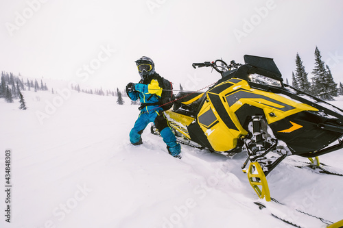  Rider on snowmobile in beautiful winter landscape with forest and mountains