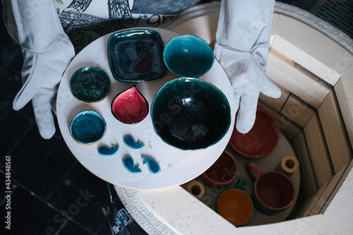 Foto Clay master Hands wearing gloves holding cups from ceramic kiln