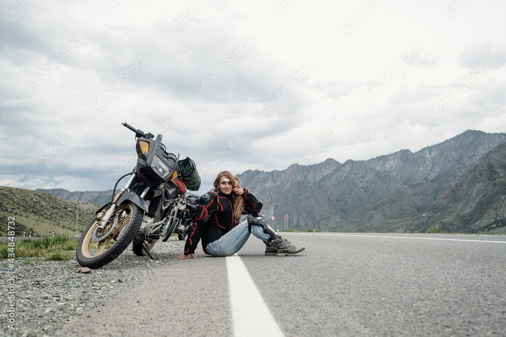 Obraz premium Female rider sitting near her motorcycle on perfect asphalt road in mountains landscape. Long travel in Altai mountain between Russia and Mongolia