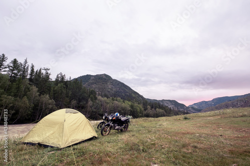 Motorcycle and tent in mountains during beautiful sunset. Moto travel