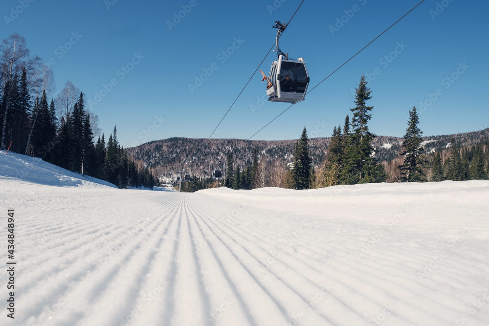 Gondola lift in the ski resort on steep slope groomed and prepared for skiing