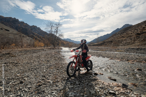 Female motorcyclist seating on Offroad enduro motorcycle in beautiful mountains near the river