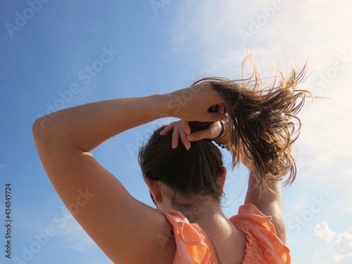 Woman putting her hair into a ponytail on a sunny day