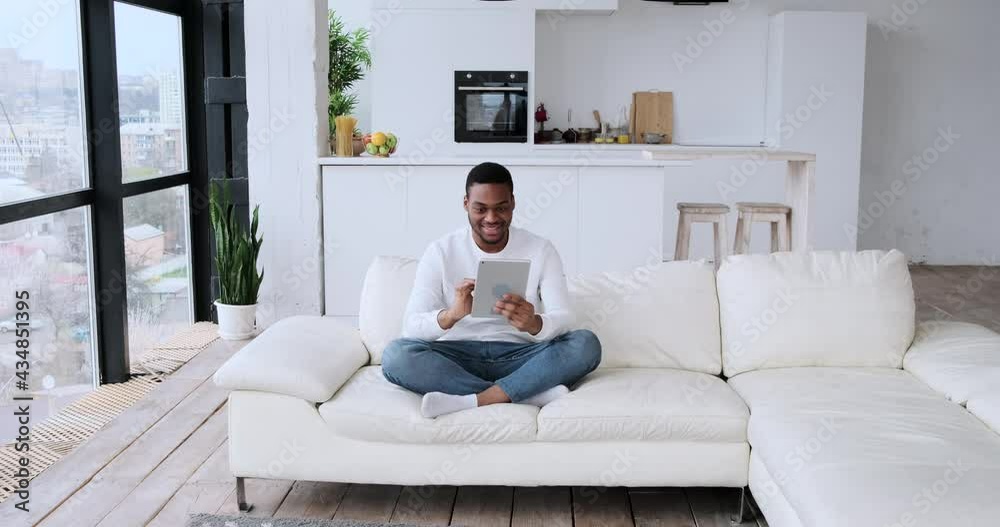 Man using digital tablet and receiving surprise gift from wife at home Man using digital tablet and receiving surprise gift from wife at home