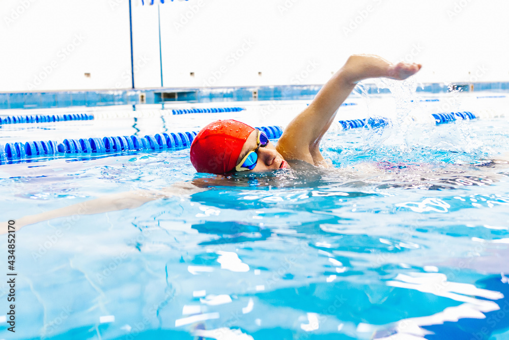 Paralympic Swimmer young latin man Training In Pool, Side view of disabled sportsman in goggles and cap in pool between lanes in disability concept